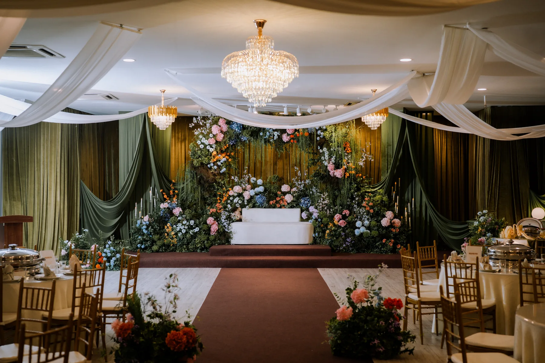 Floral reception stage and dining setup inside Luminare Hall